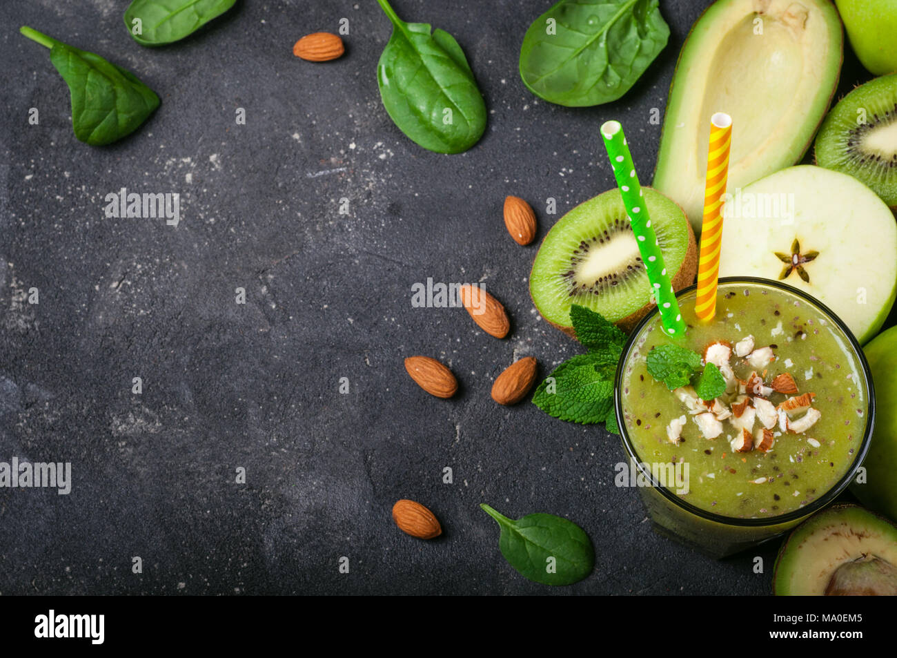 Un sano frullato verde e gli ingredienti su sfondo scuro. Frullato di kiwi con frutti di mandorle e noci. Superfoods, dieta disintossicante, salute cibo vegetariano Foto Stock