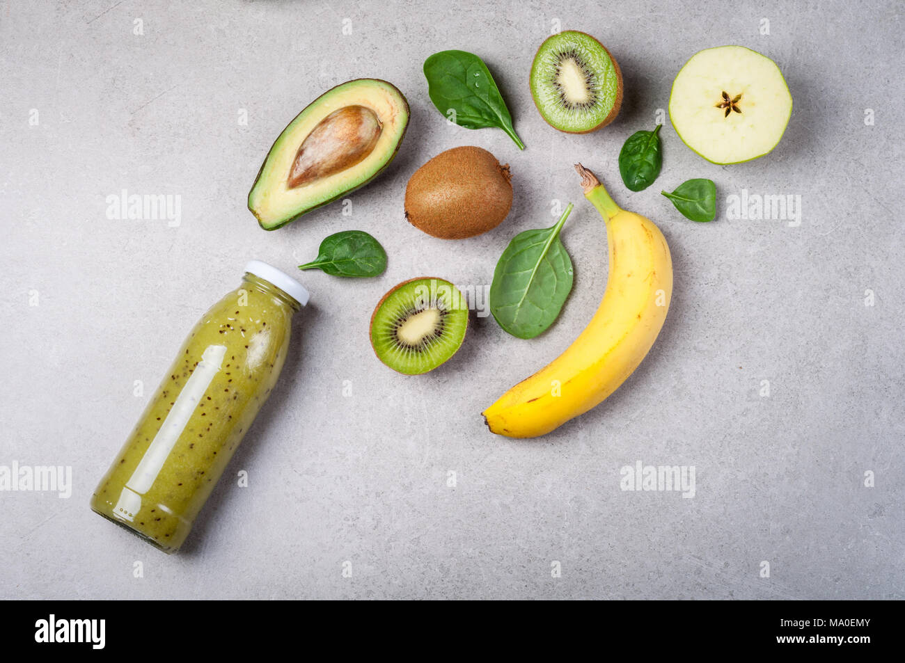 Un sano frullato verde e gli ingredienti su sfondo grigio. Frullato di kiwi con la frutta e la verdura. Superfoods, dieta disintossicante, salute cibo vegetariano Foto Stock
