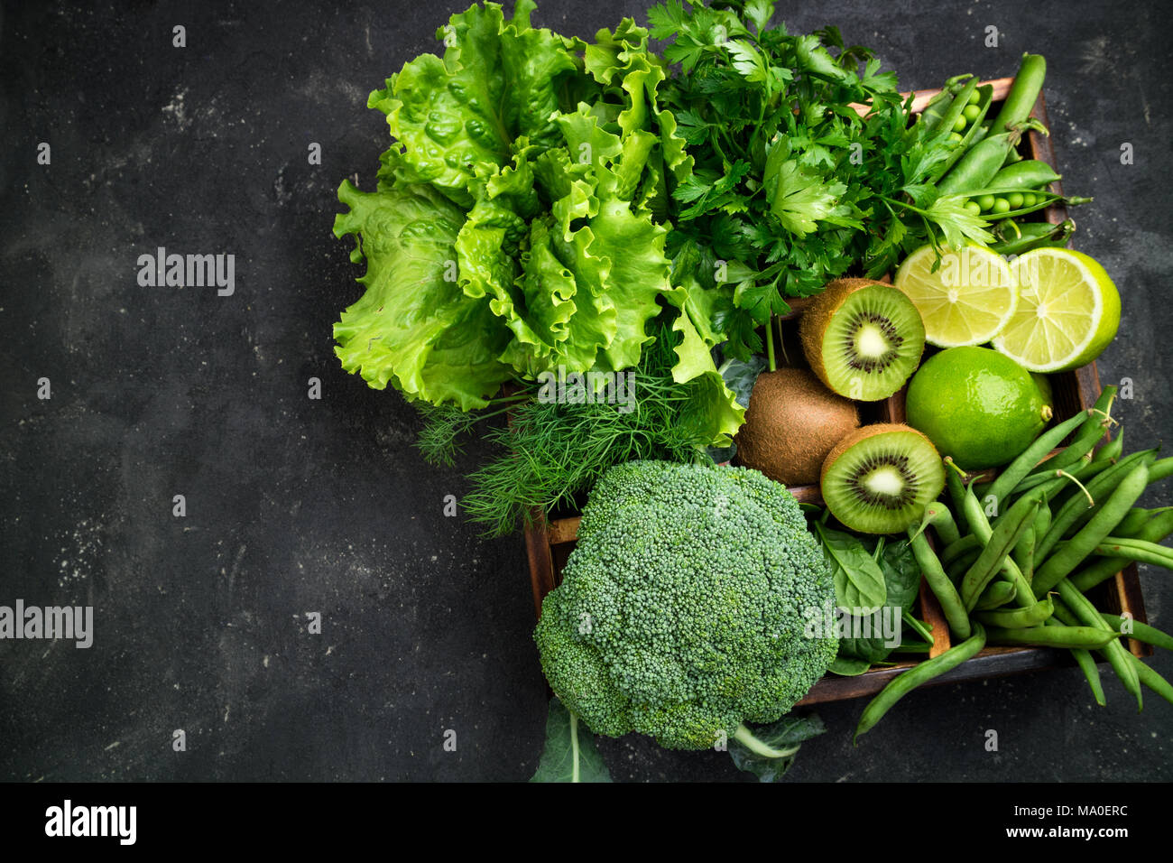 Verdure verdi. Broccoli, spinaci, kiwi, lattuga, prezzemolo, aneto, Fagioli Asparagi sul calcestruzzo scuro tavolo. Cibo vegetariano. Vista superiore Foto Stock