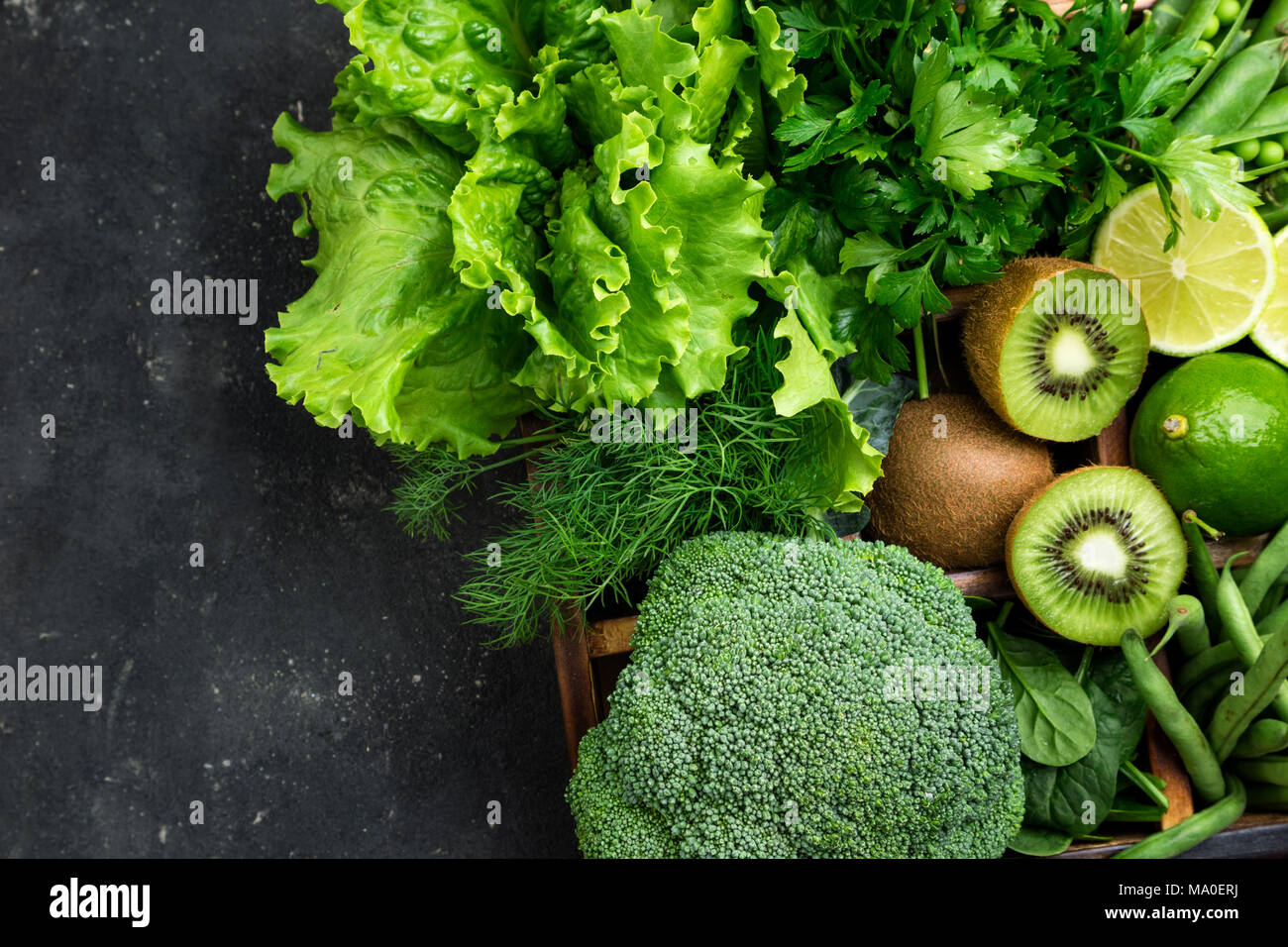 Verdure verdi. Broccoli, spinaci, kiwi, lattuga, prezzemolo, aneto, Fagioli Asparagi sul calcestruzzo scuro tavolo. Cibo vegetariano. Vista superiore Foto Stock