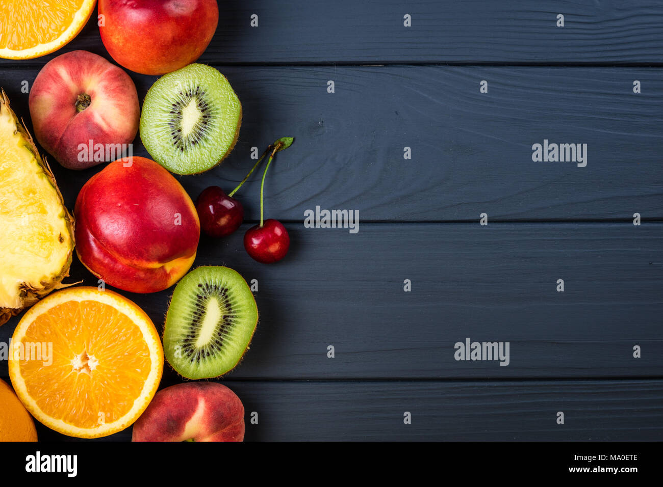 Frutti e bacche. Assortimento di frutta esotica. Cibo sano e background. Ananas, pesche, kiwi, agrumi e ciliegio Foto Stock