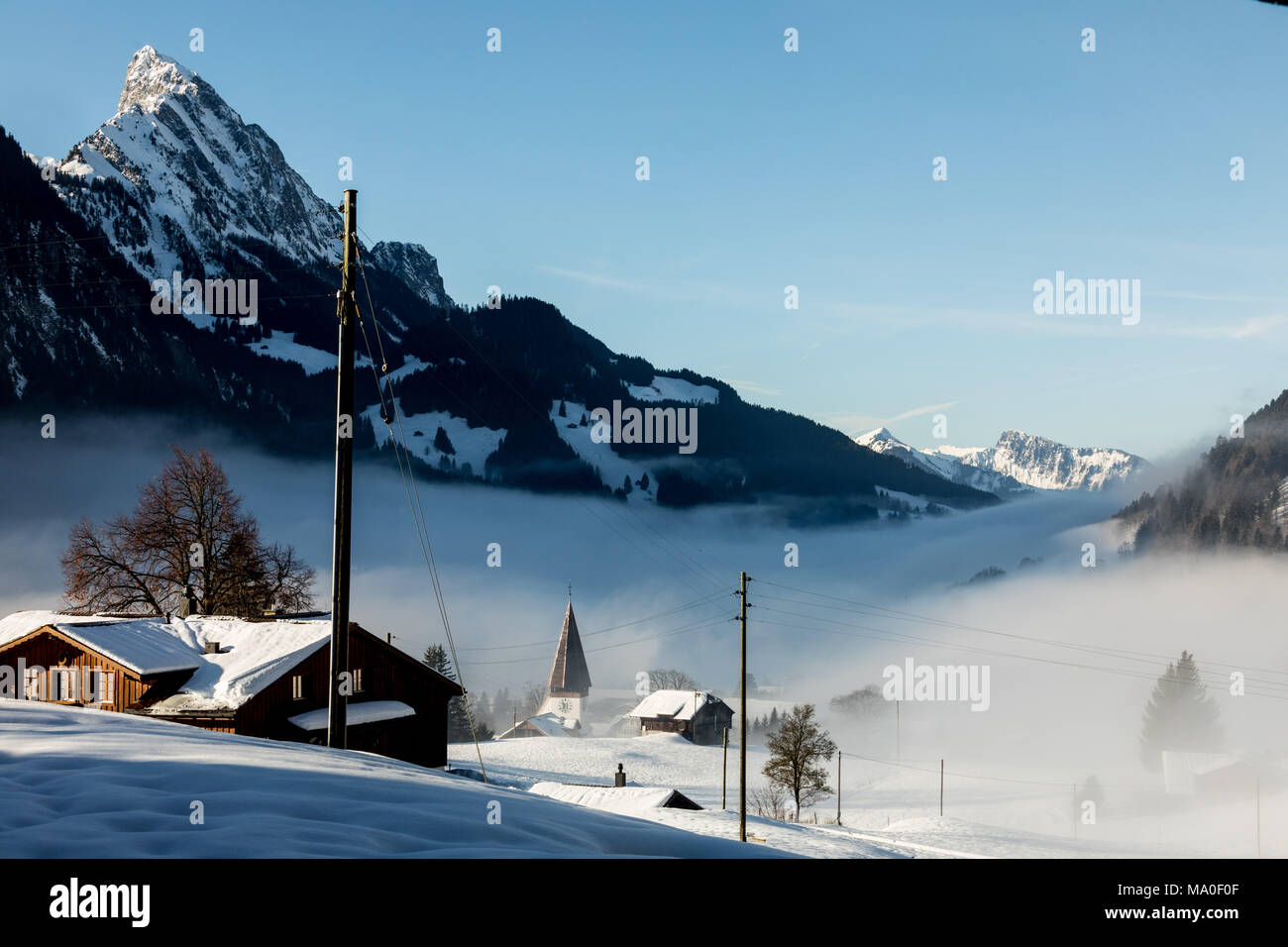 Villaggio di montagna delle Alpi coperte di neve e nuvole Foto Stock