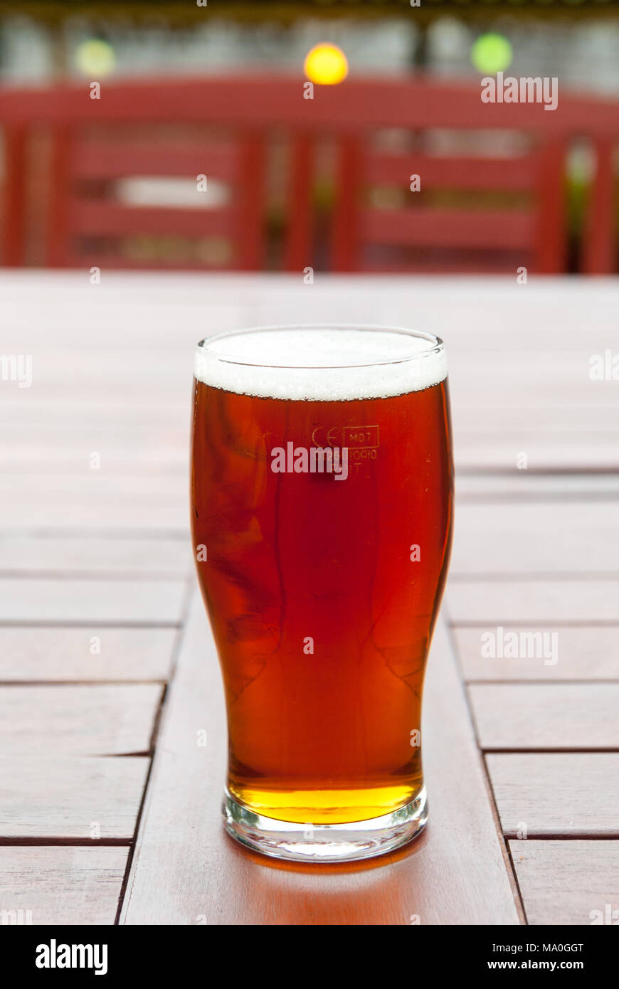 Una pinta di birra calda, bruna, inglese, birra reale su un pub birreria tavolo giardino nel rurale Hampshire, Inghilterra, Regno Unito Foto Stock