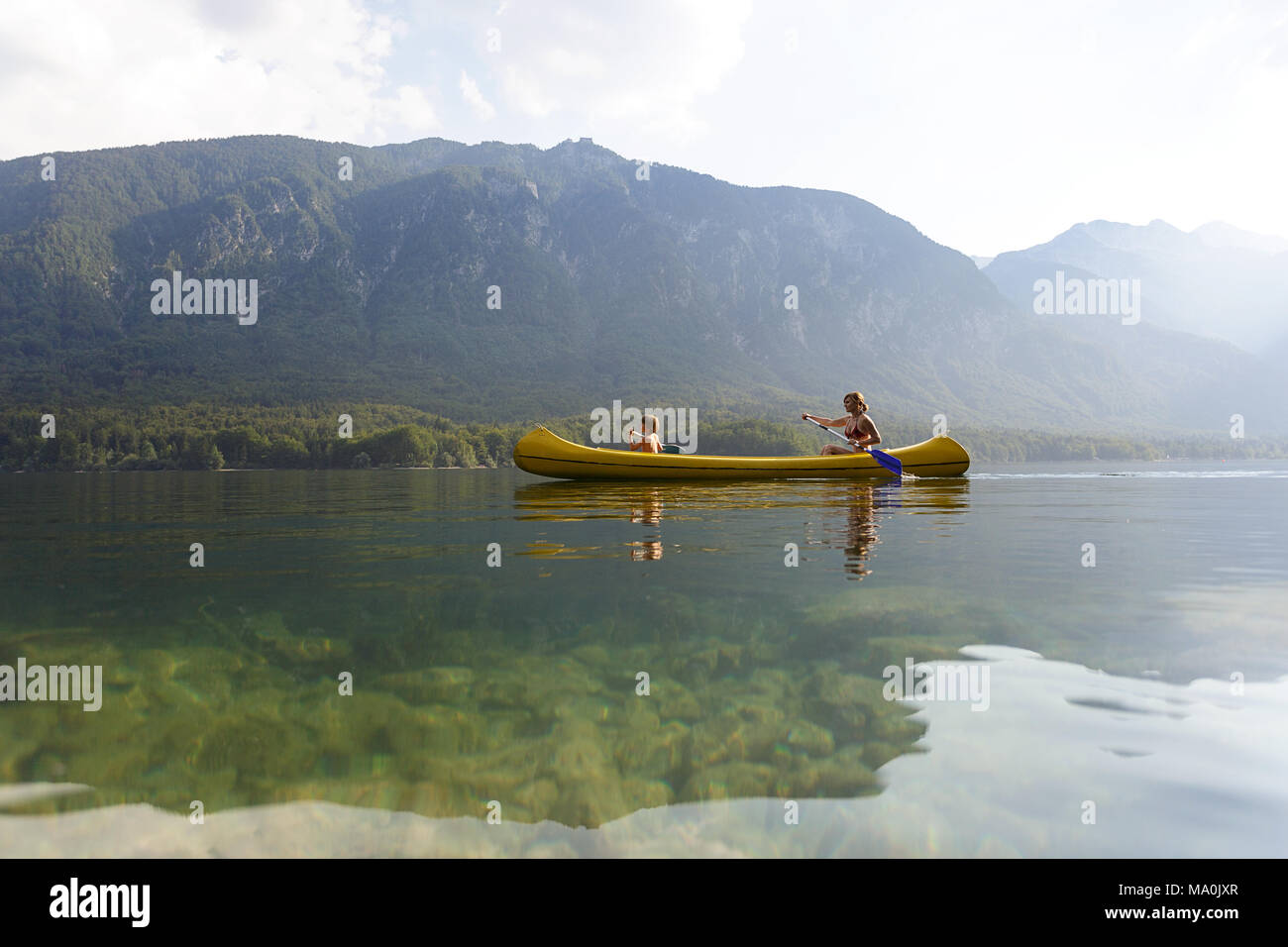 Una madre e il suo figlio di 5 anni canoe su un lago alpino nelle Alpi Giulie Foto Stock