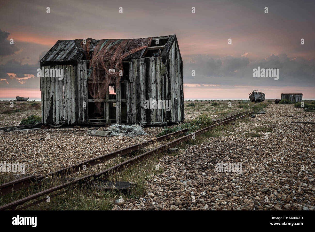 Un vecchio capannone abbandonato sulla spiaggia di ciottoli di Dungeness in Kent, appena prima del sorgere del sole le prime luci dell alba aggiunge un po' di colore al cielo. Foto Stock