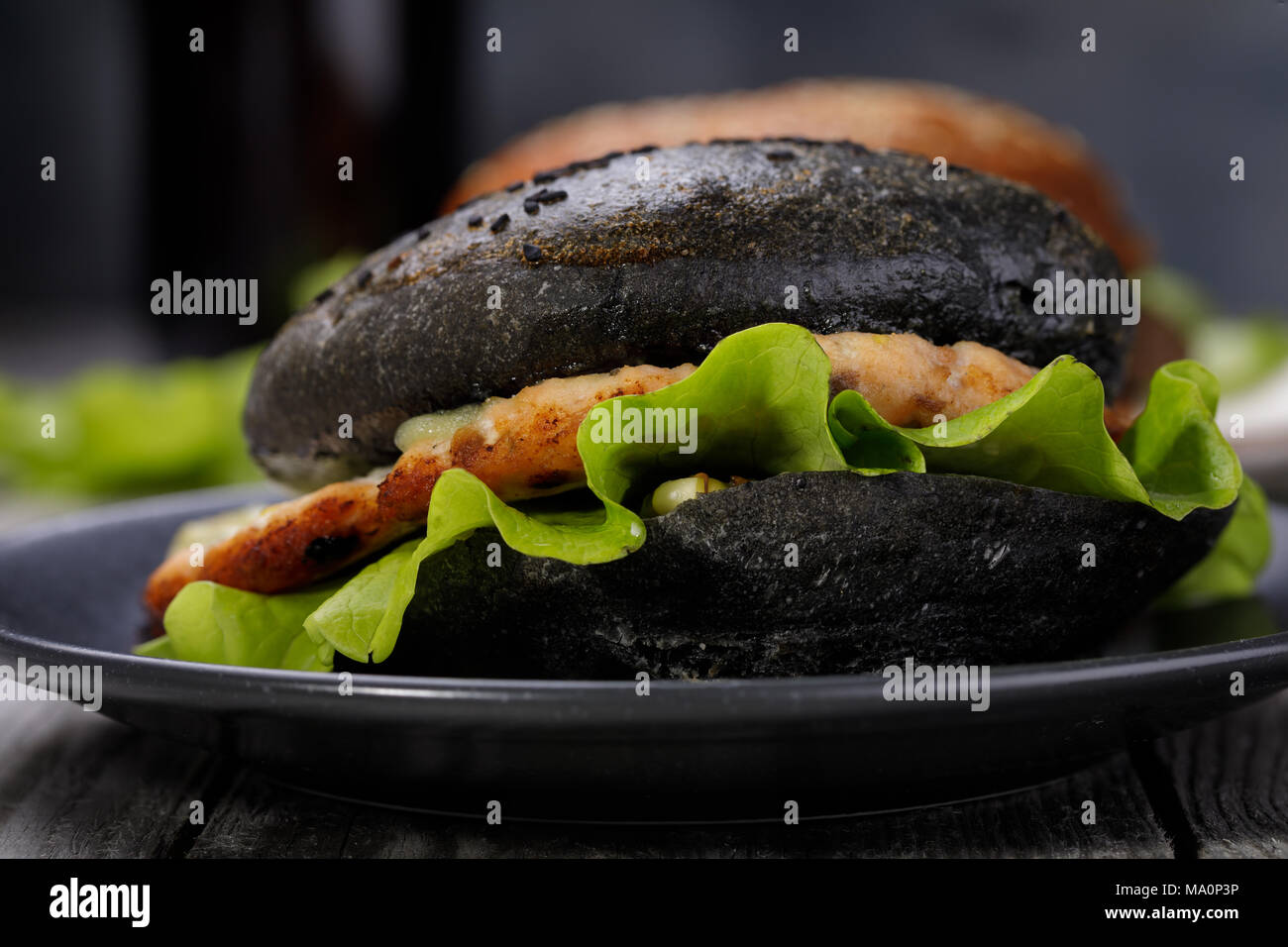 Cucinata fresca hamburger con rotolo di colore nero, verdure e salmone cotoletta. Sandwich fatti in casa closeup Foto Stock