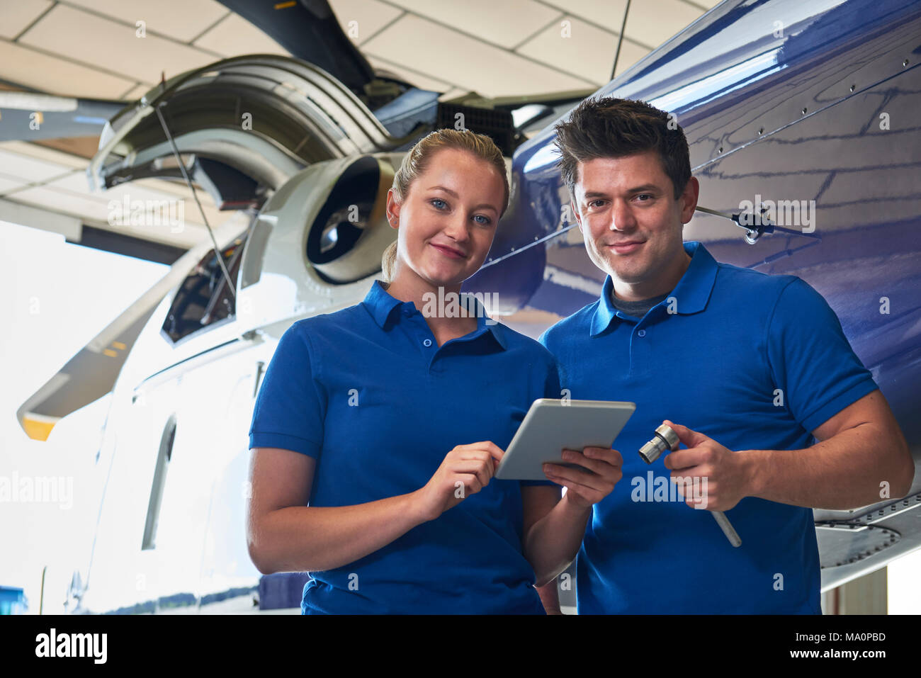 Ritratto di Aero ingegnere e apprendista Lavorare in elicottero in hangar guardando a tavoletta digitale Foto Stock