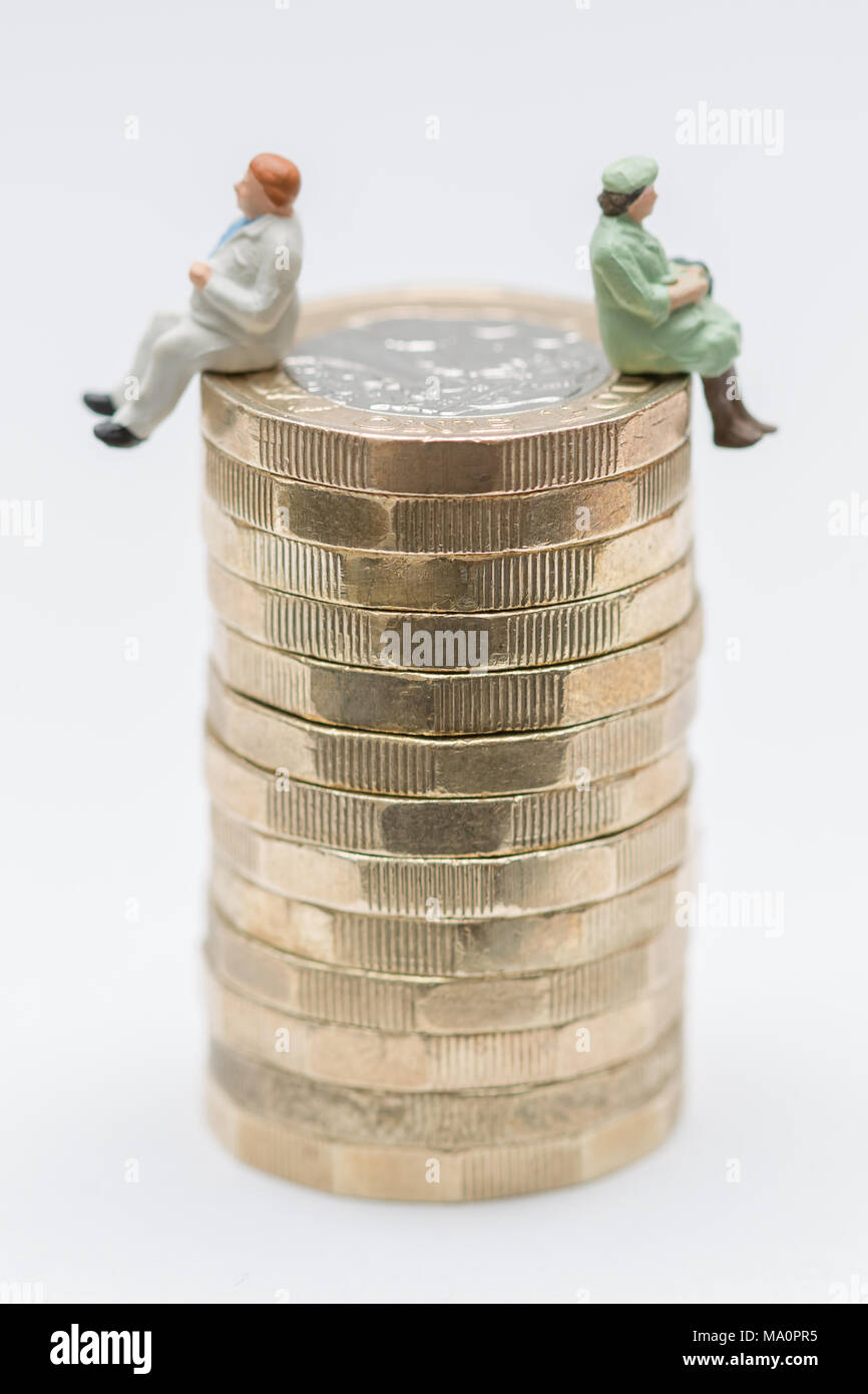 Sesso pagare la parità Concetto di immagine di un uomo e di una donna su una pila di libbra di monete Foto Stock