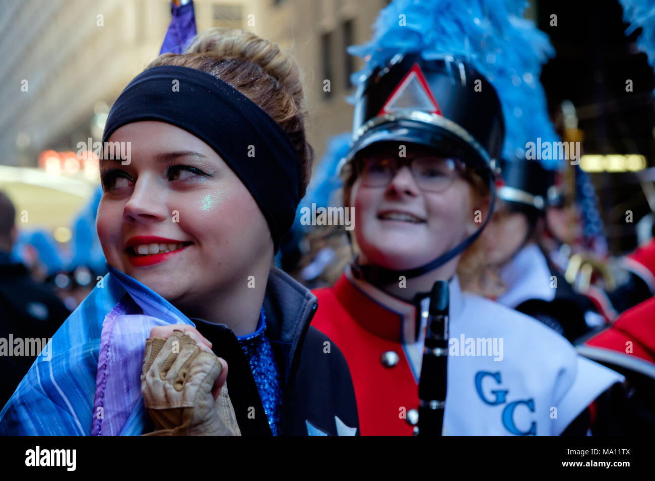 Alta scuola ragazza sorridente sulla spalla & holding bandiera nella festa di San Patrizio Parade di New York, 2018.altro studente sorridente dietro. Brilla sul viso. Foto Stock