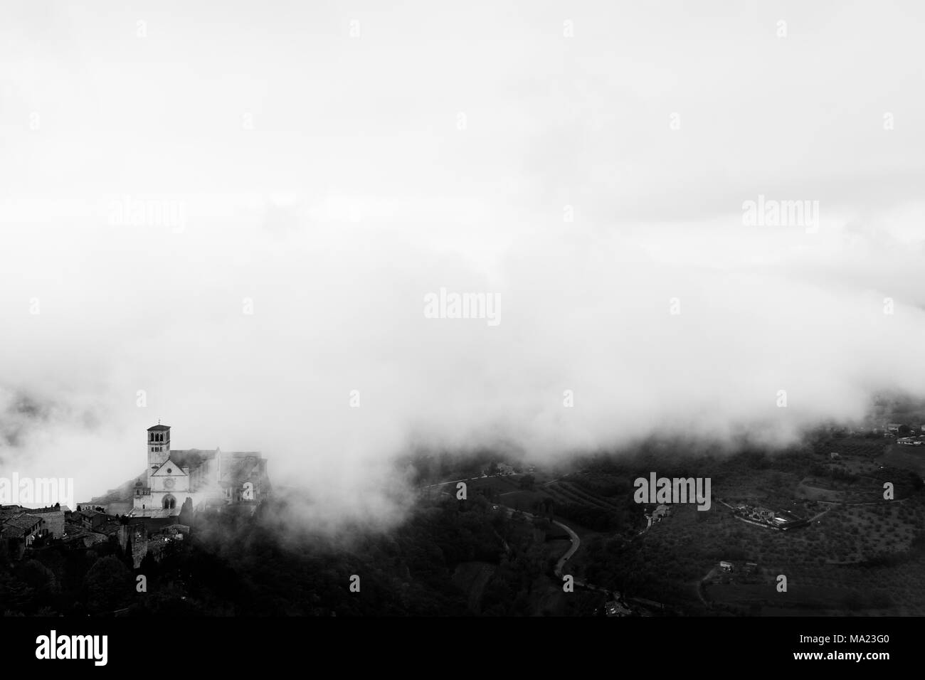 Vista di San Francesco chiesa papale in Assisi (Umbria, Italia), nel mezzo di sollevamento di nebbia di mattina Foto Stock