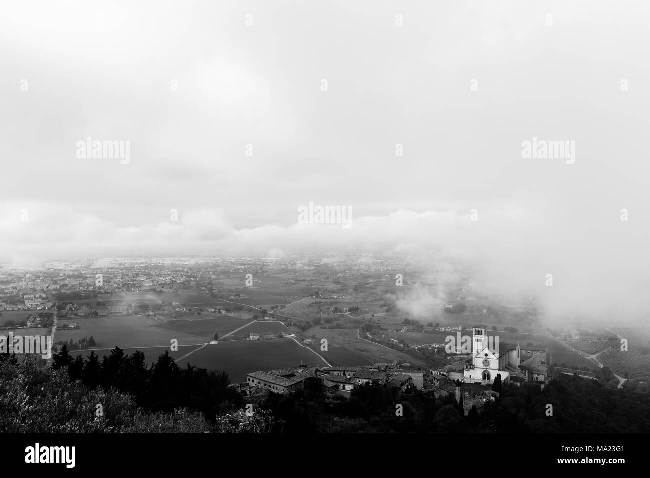 Vista di San Francesco chiesa papale in Assisi (Umbria, Italia), nel mezzo di sollevamento di nebbia di mattina Foto Stock