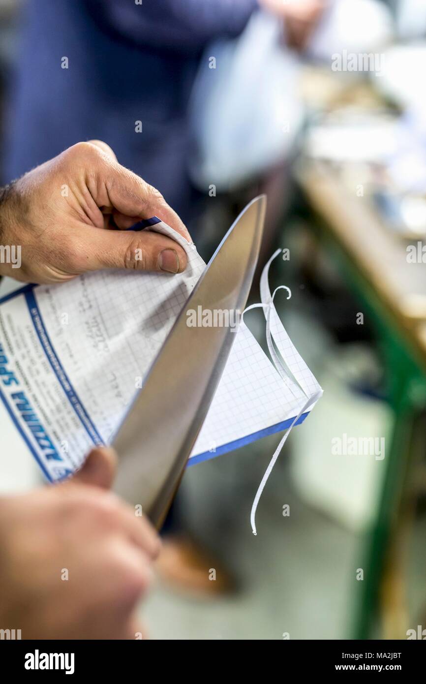 Un test di taglio con un coltello da cucina italiana in uno stabilimento di coltello Foto Stock
