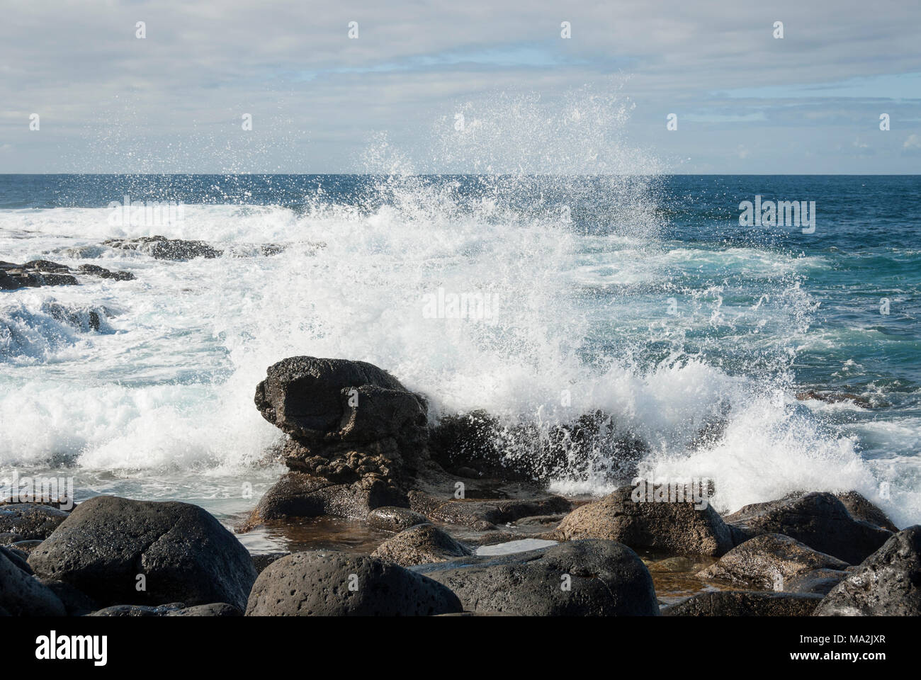 Onde gli spruzzi di acqua sulle rocce della costa di Lanzarote Foto Stock
