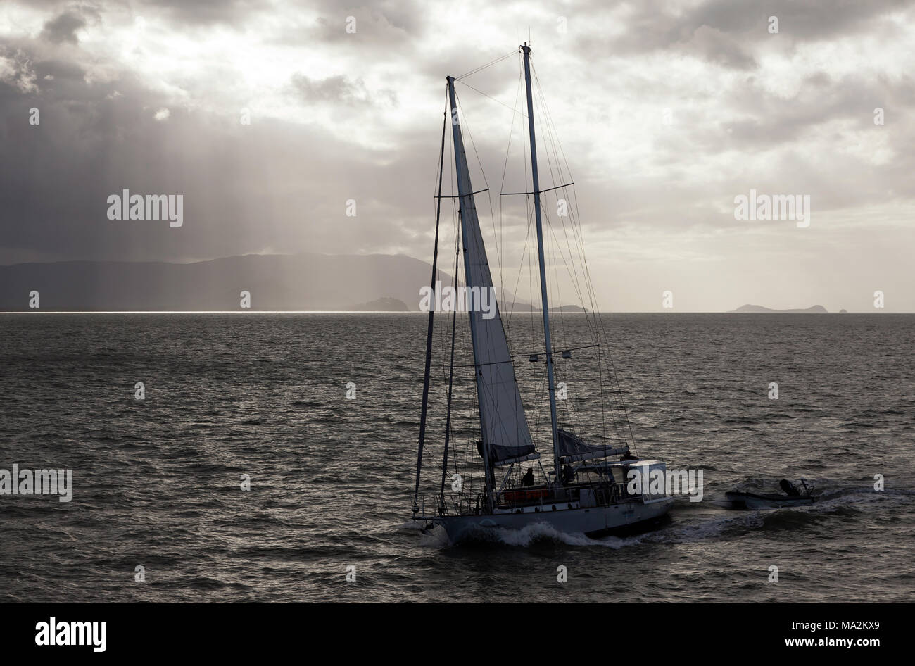 Barca a vela di ritornare a Cairns Seaport, in drammatiche condizioni di luce Foto Stock