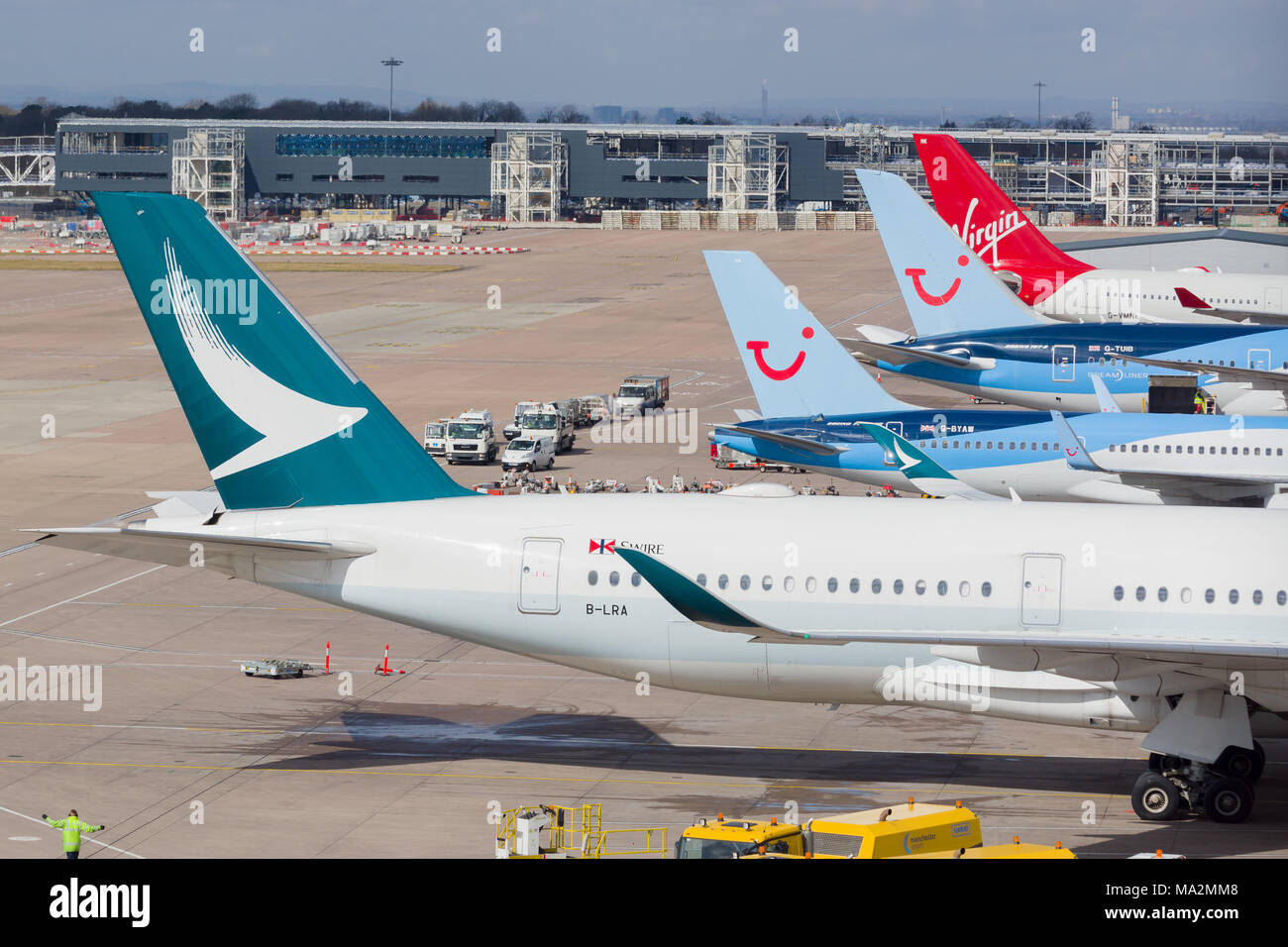 Diverse alette di coda di aerei di linea tra cui Cathay Pacific, Tui e Virgin parcheggiato al terminal 2 nell'aeroporto di Manchester Foto Stock