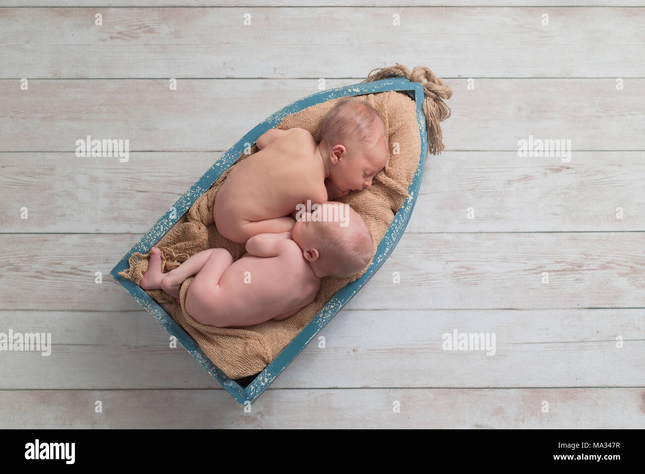 Sei giorni di vita fraterna, twin, neonato, baby boys dormire in una piccola barca di legno. Girato in studio su un sfondo di legno. Foto Stock