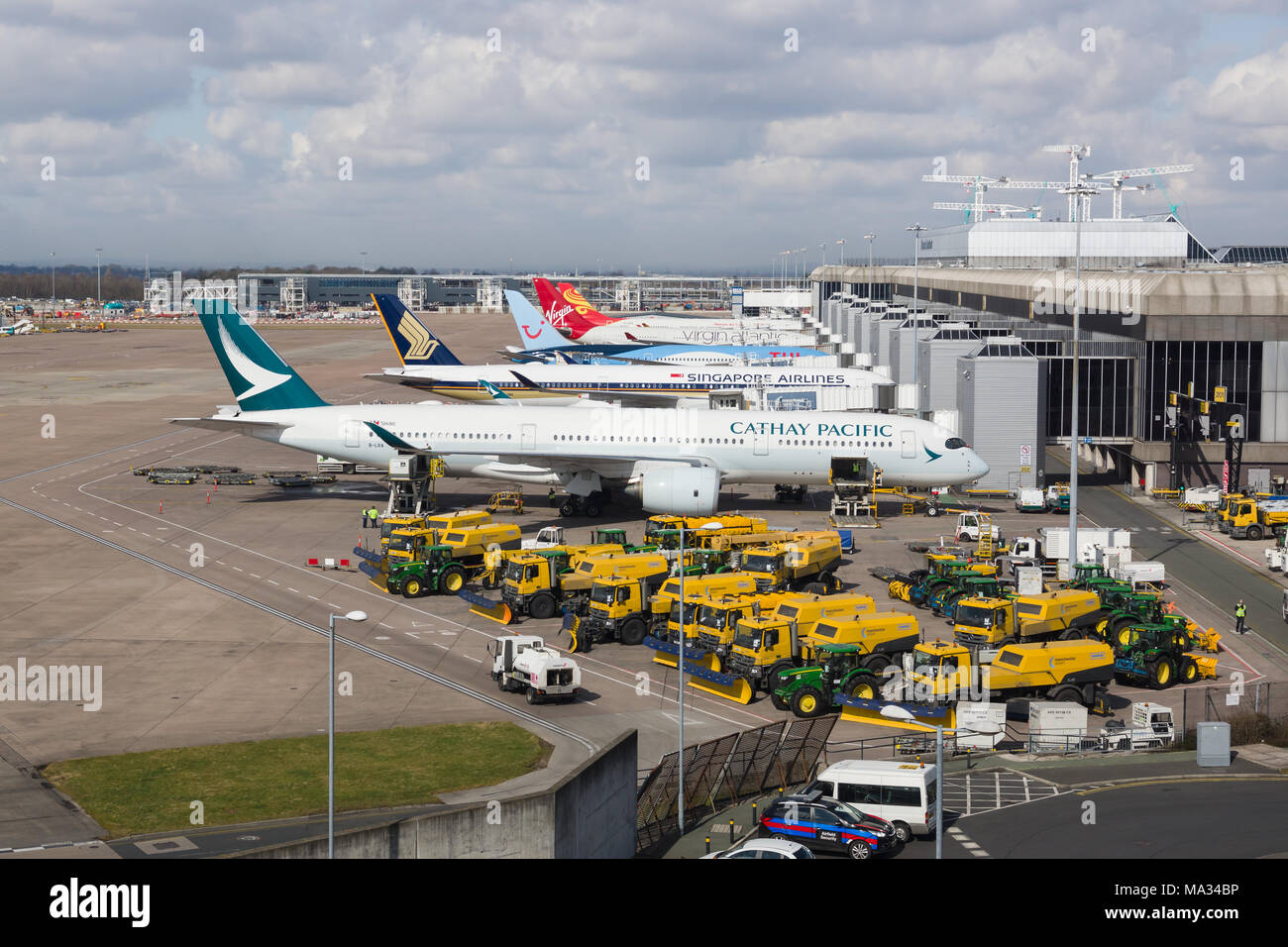 Vari aeroplani e manutenzione veicoli parcheggiati al terminal 2 nell'aeroporto di Manchester Foto Stock