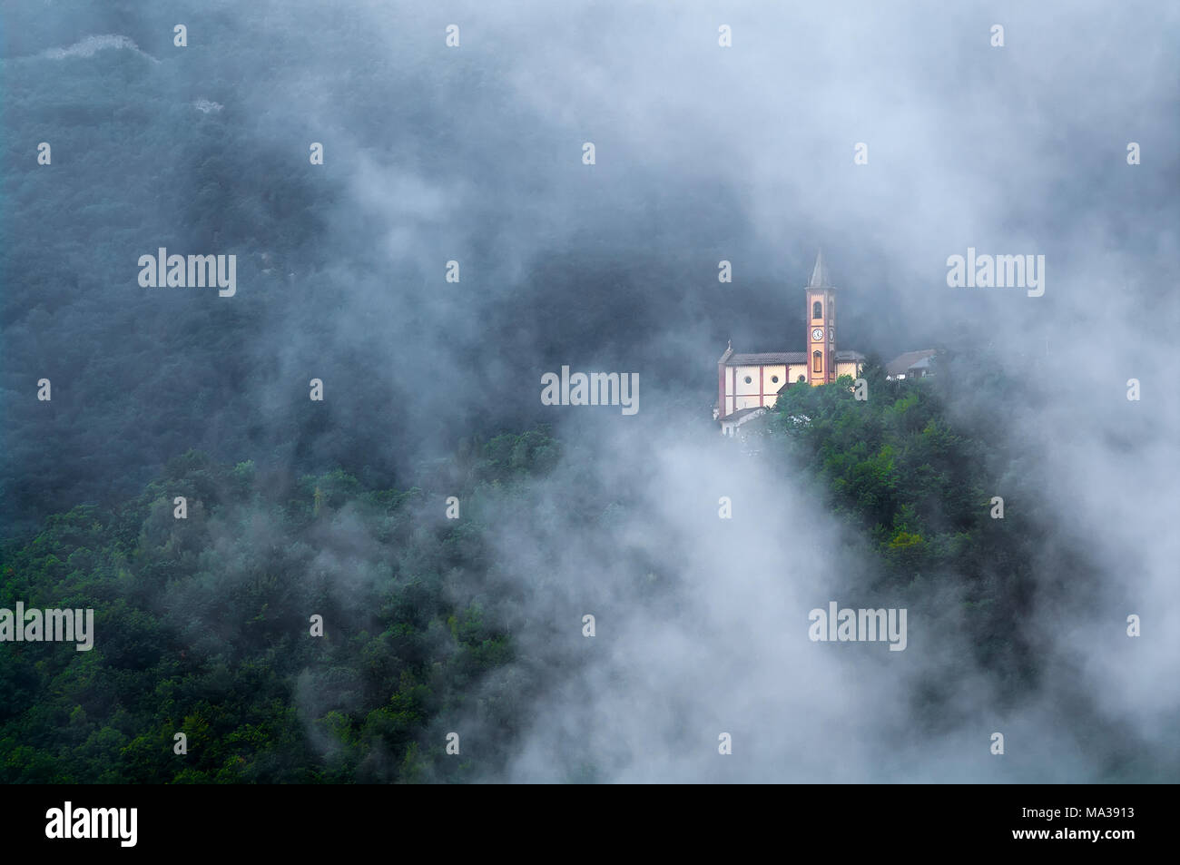 La chiesa del villaggio di cappello, comune di Garessio, in Alta Valle Tanaro (MI), circondato dalla nebbia che risale dalla valle Foto Stock