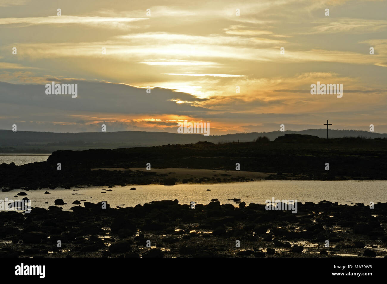 Isola di St. Cuthbert, Northumberland al tramonto e con la croce in silhouette Foto Stock