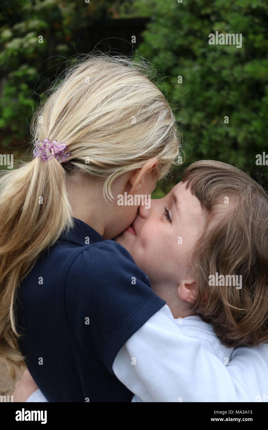 Due sorelle abbracciando e dando un peck sulla guancia Foto Stock