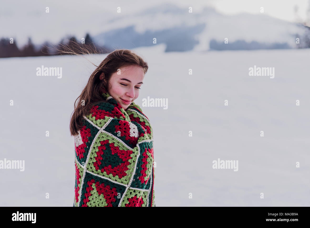 Giovane donna avvolta in una coperta è in piedi nella neve, Foto Stock