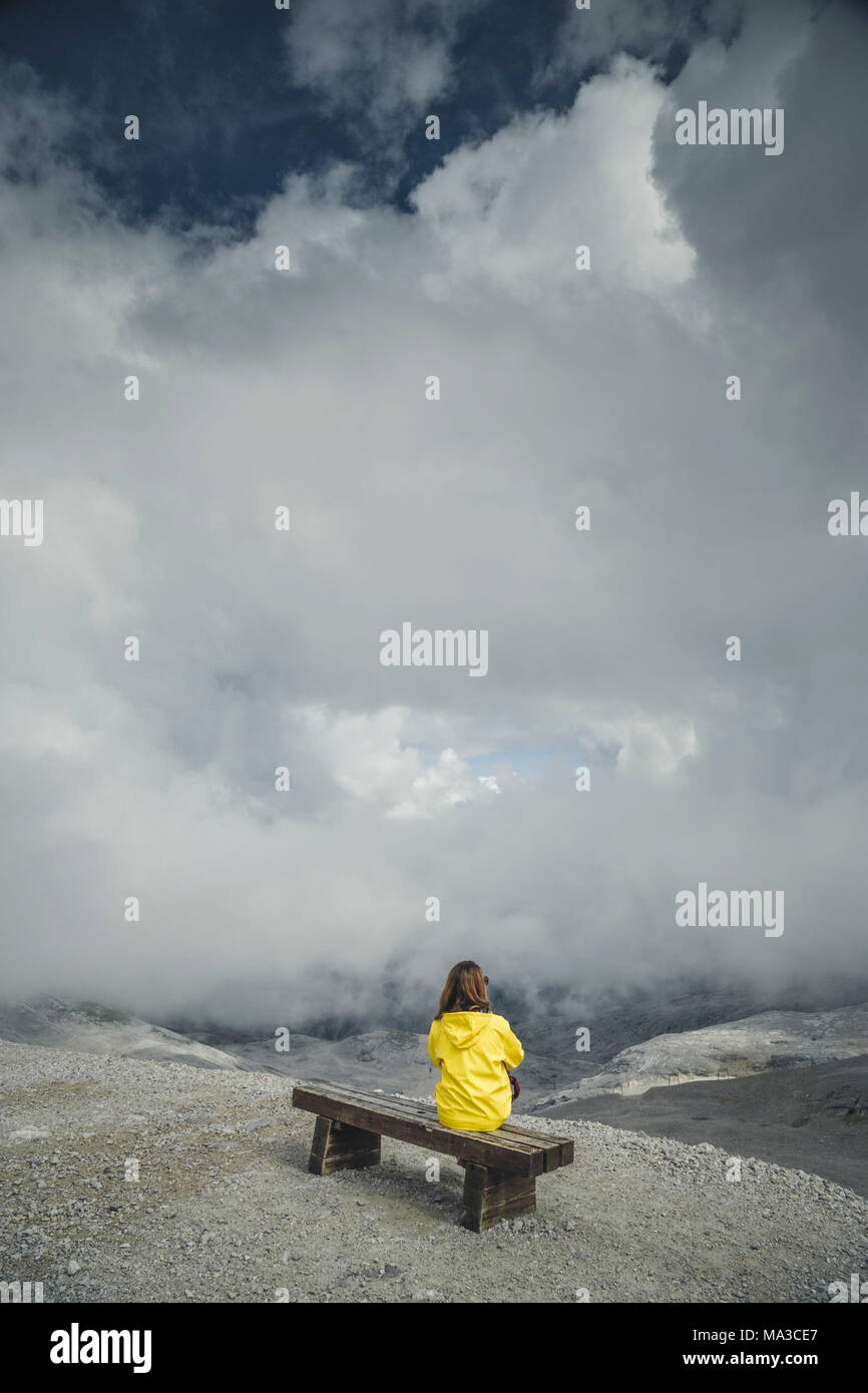 Una ragazza con un impermeabile gialla sulla parte superiore del ghiacciaio Zugspitze. Garmisch Partenkirchen, Bayern Alpi, Germania. Foto Stock