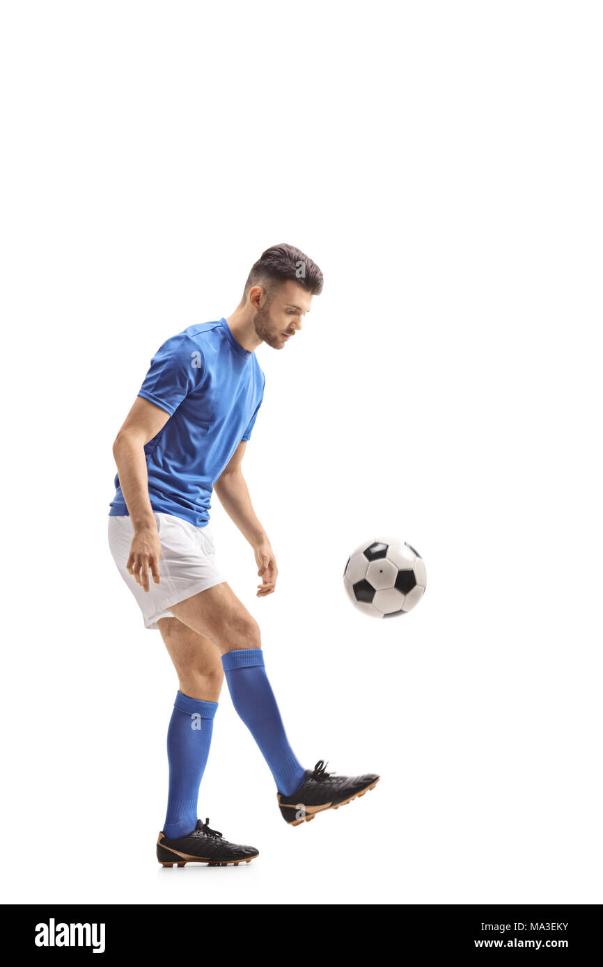Lunghezza piena ripresa di profilo di un giocatore di calcio con un pallone da calcio isolati su sfondo bianco Foto Stock