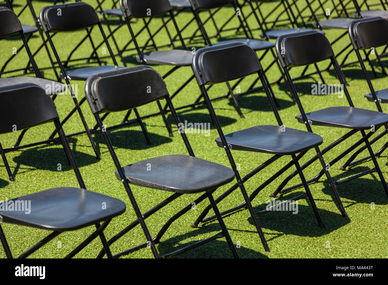 Righe di nero sedie pieghevoli setup per un evento esterno. Foto Stock
