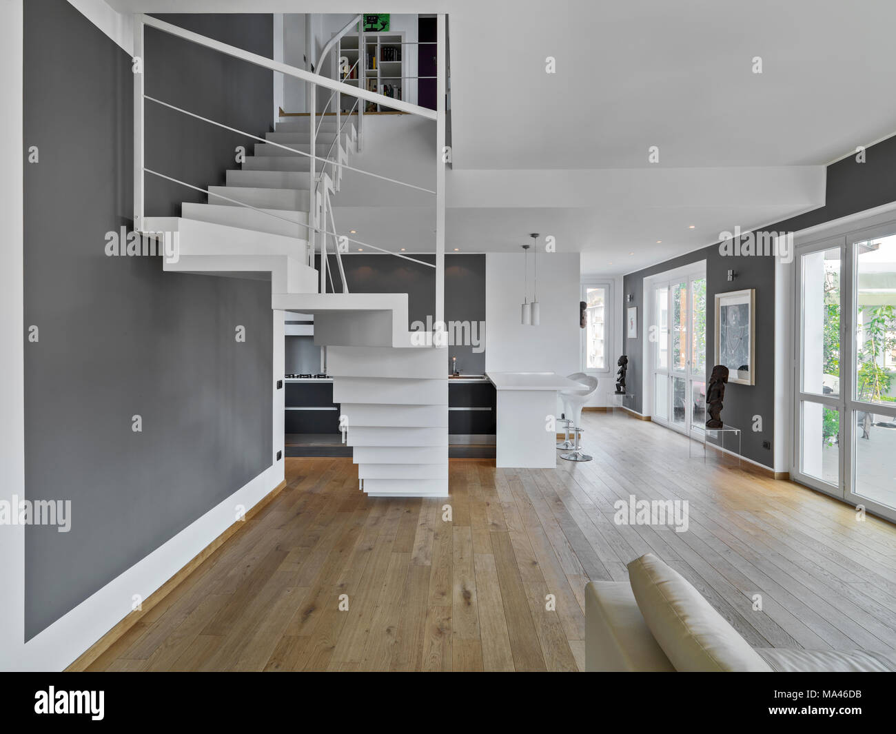 Scatti di interni di un moderno appartamento in primo piano la scala in ferro sullo sfondo la cucina mentre il pavimento è in legno Foto Stock