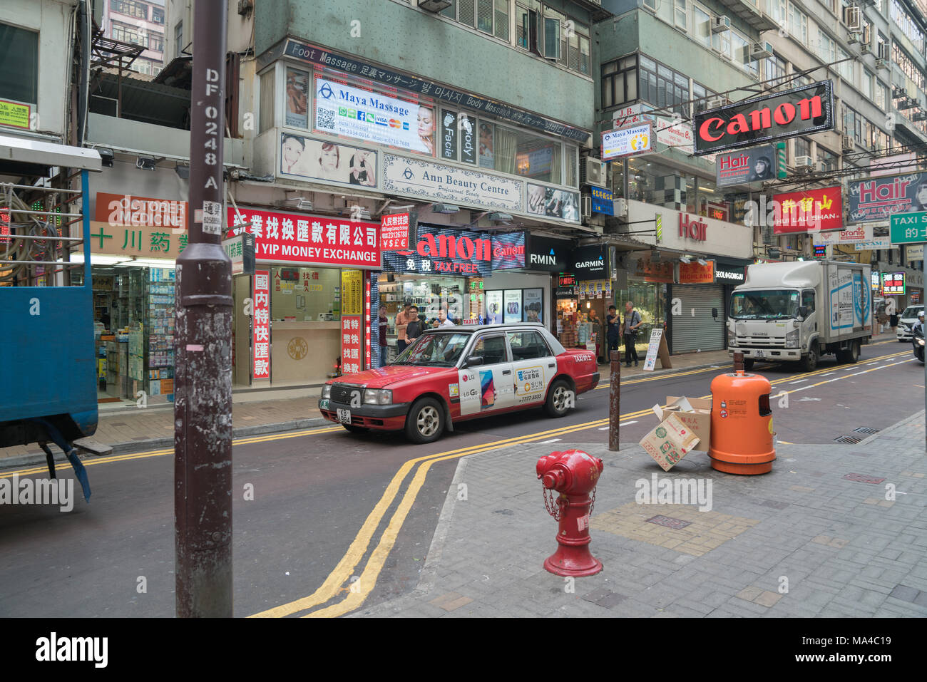 KOWLOON, HONG KONG - 18 settembre 2017; tipicamente Asian downtown city street scene con veicoli, taxi occupato segni commerciali e pubblicità emblazon Foto Stock