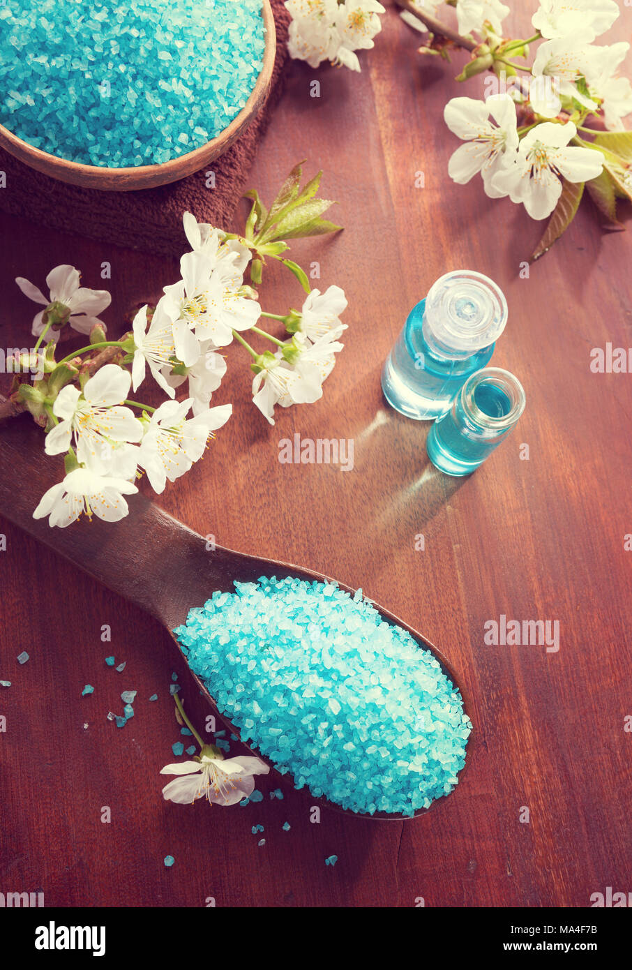 Bagno minerale sali, gel doccia, asciugamani e fiori sul tavolo di legno. Spa concept Foto Stock