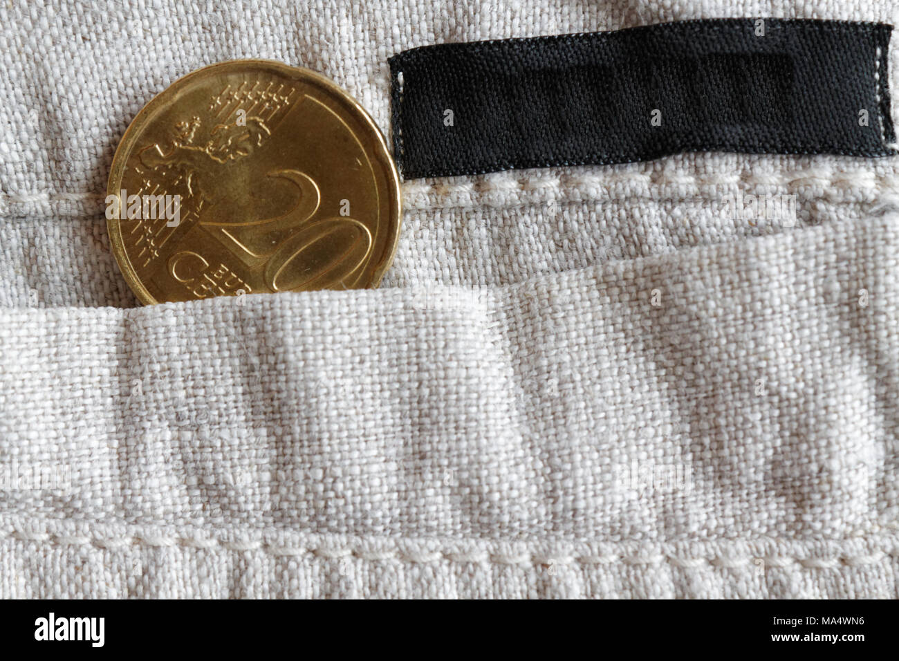 Monete in euro con una denominazione di 20 centesimi di euro nella tasca dei pantaloni di lino con striscia nera Foto Stock