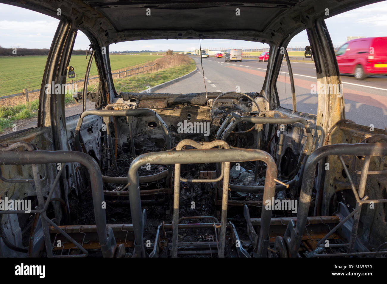Interni danneggiati abbandonato bruciato auto rimane a lato della strada, REGNO UNITO Foto Stock