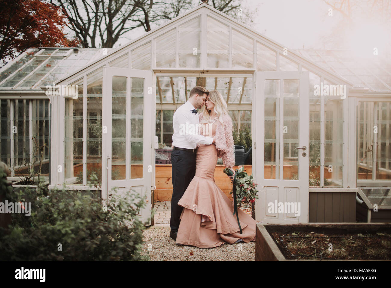 Coppia di sposi in piedi in giardino, abbraccio, Foto Stock