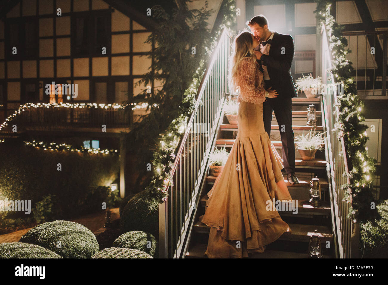 Coppia di sposi stand su una scalinata e baciate Foto Stock