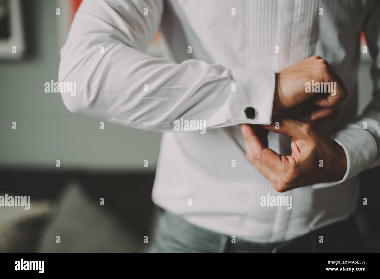 L'uomo mette sulla sua maglietta, chiusura cufflink, dettaglio Foto Stock