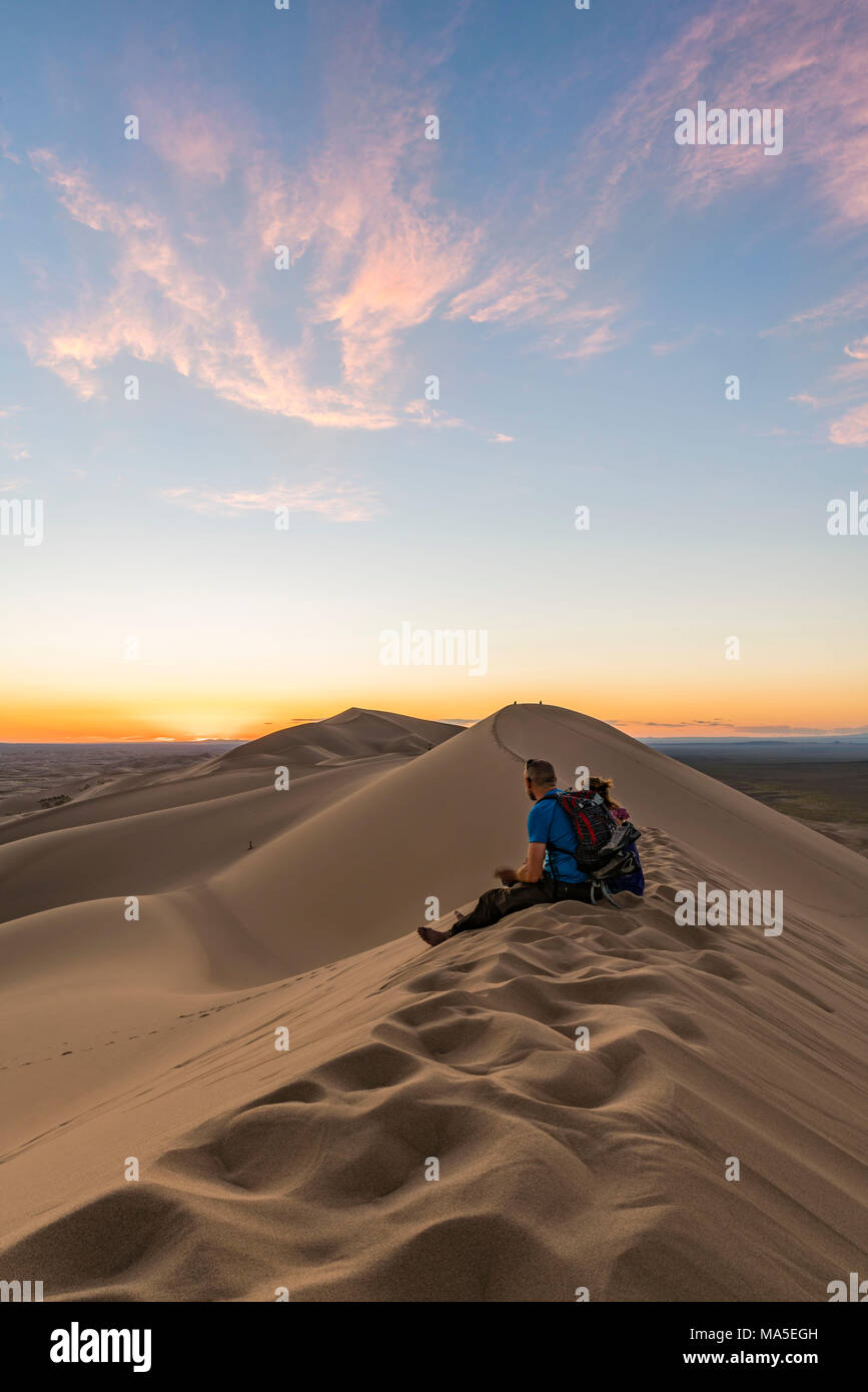 L'uomo a guardare il tramonto nel Gobi Gurvan Saikhan Parco Nazionale. Sevrei distretto, a sud della provincia di Gobi, Mongolia. Foto Stock