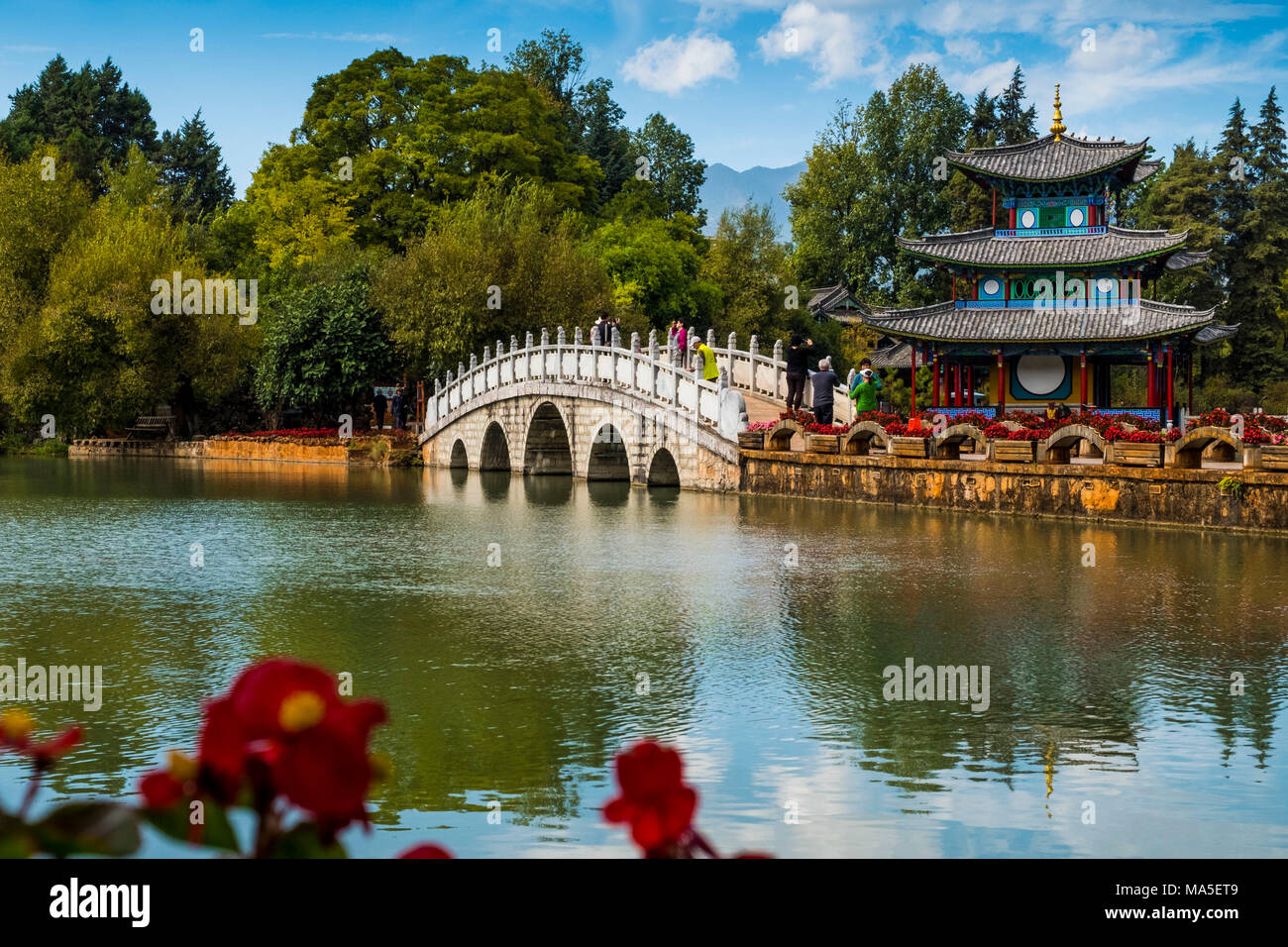 I turisti oltre il ponte ad arcate al Black Dragon Pool, Lijiang, nella provincia dello Yunnan in Cina, Asia, Asia, Asia orientale, Estremo Oriente Foto Stock