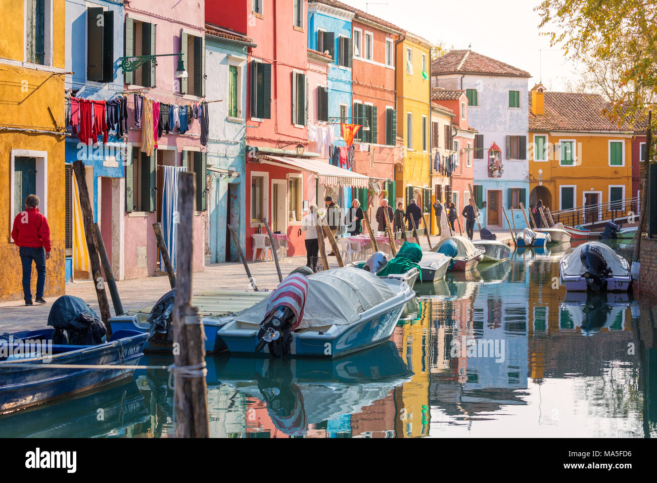 Una vivace strada di Burano, le case colorate si affacciano sul canale e la gente a piedi, isola di Burano, Venezia, Veneto, Italia Foto Stock