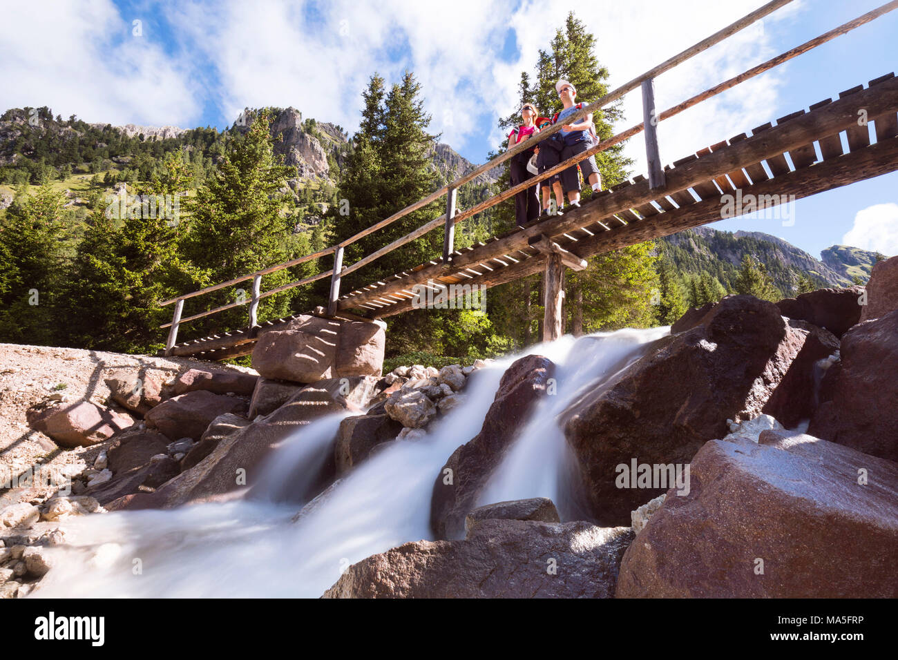Una famiglia su un ponte di legno lungo un sentiero in Villnössertal, Provincia Autonoma di Bolzano Alto Adige, Trentino Alto Adige, Italia Foto Stock