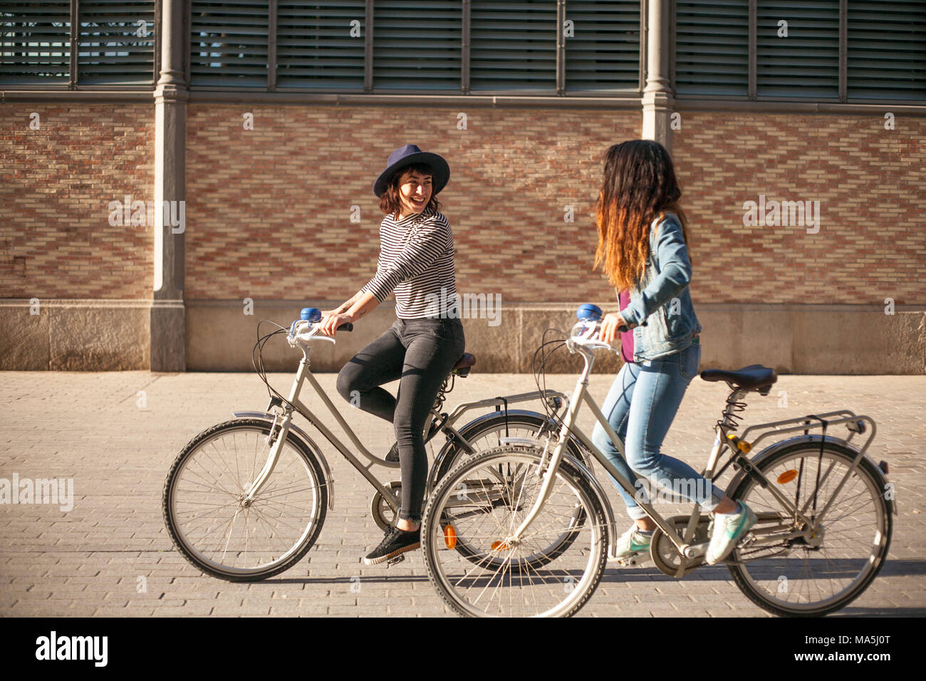 Due giovani donne in bicicletta a Barcellona, in Catalogna, Spagna Foto Stock