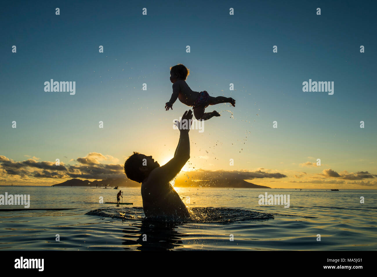 Padre giocando con il bambino in acqua, Papeete, Tahiti, Polinesia Francese Foto Stock