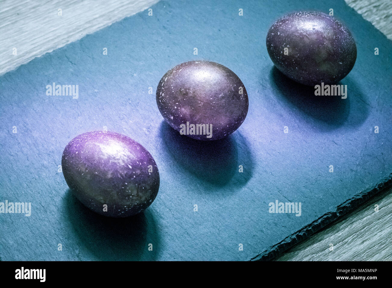 Pasqua spazio cosmico oro viola uova colorate sulla cucina ardesia tagliere Foto Stock