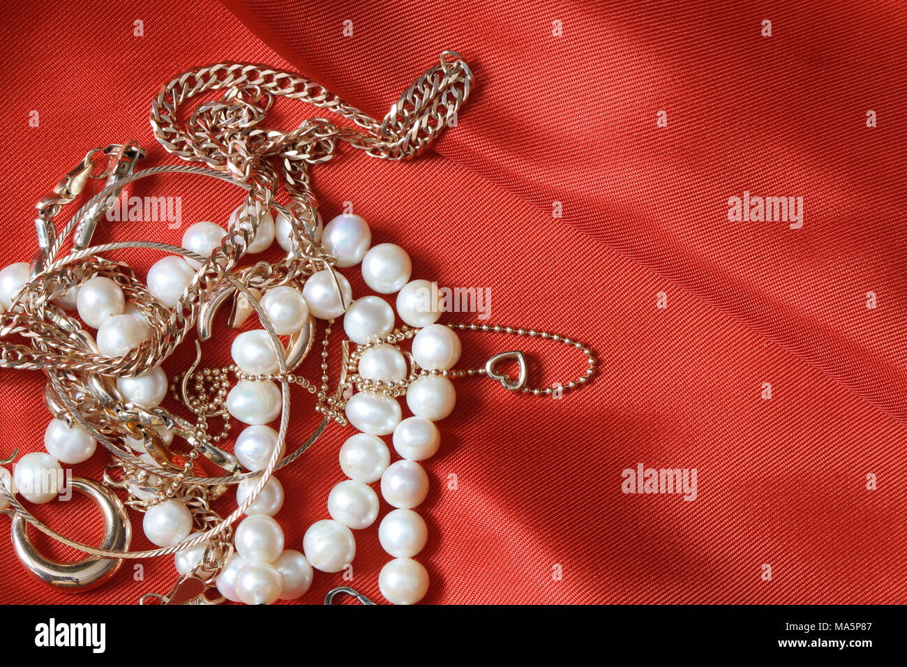 Collana di perle e gioielli in oro giacente su di seta rossa con sfondo  spazio copia Foto stock - Alamy