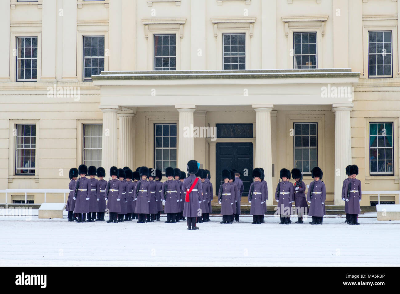 Irlandese guardie dal Queens reggimenti di guardia la preparazione per la cerimonia del Cambio della Guardia con un sopralluogo nella neve alla caserma di Wellington Foto Stock