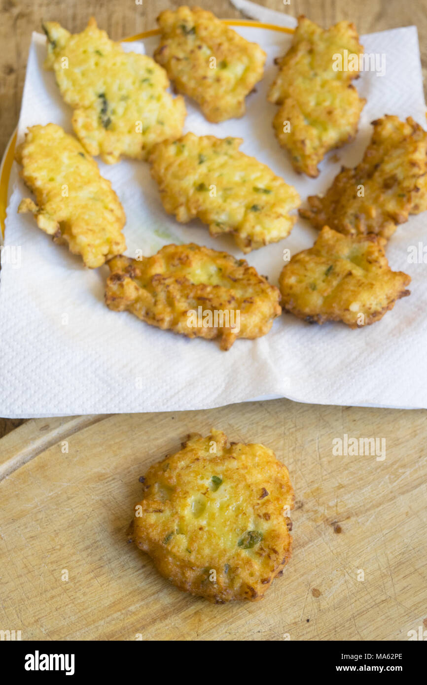 Single fritti crocchette di mais vicino a un piatto pieno della stessa frittelle croccanti Foto Stock