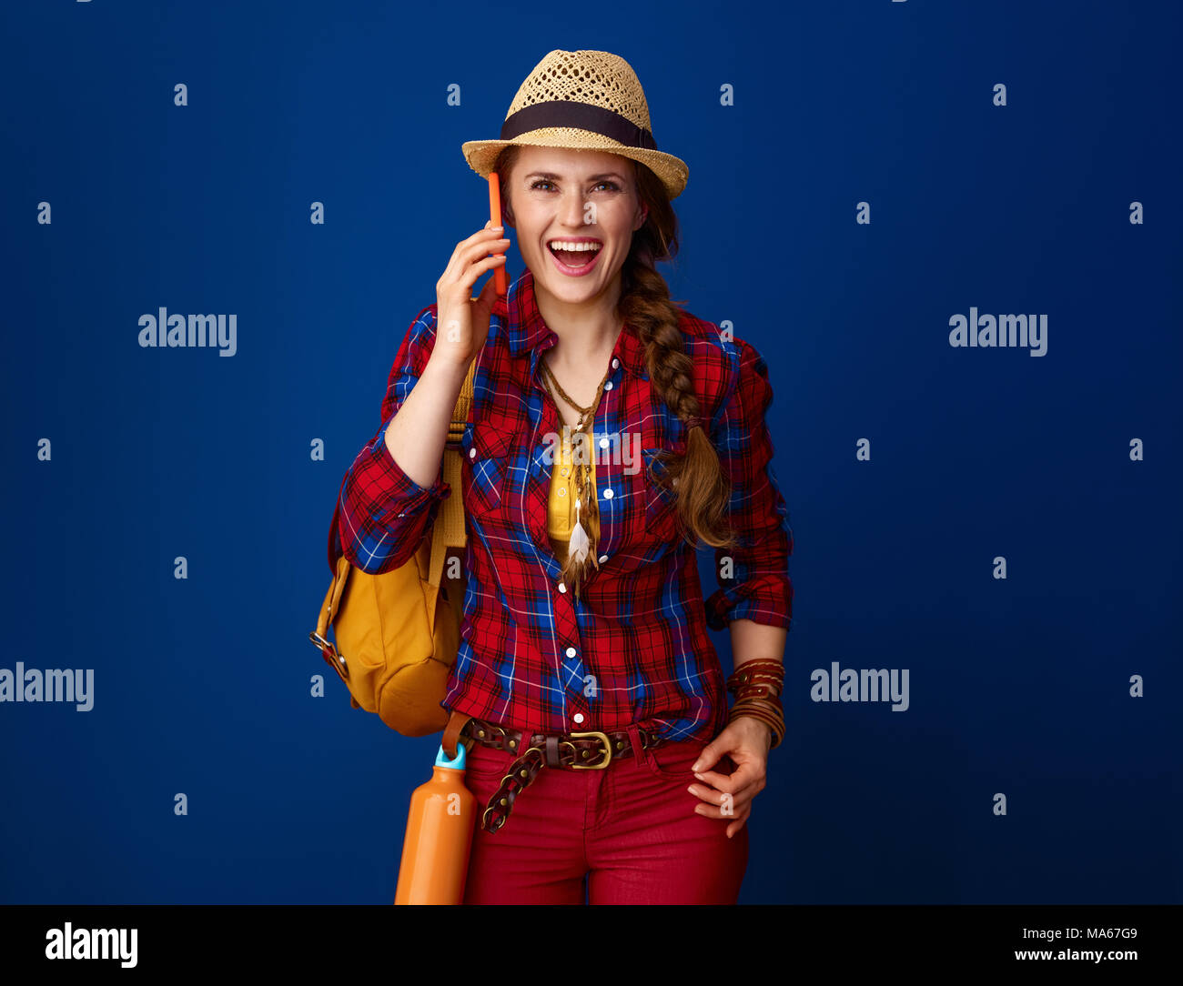 La ricerca di luoghi ispiratrice. sorpreso avventura Excited donna escursionista in un plaid shirt utilizzando uno smartphone isolato su blu Foto Stock