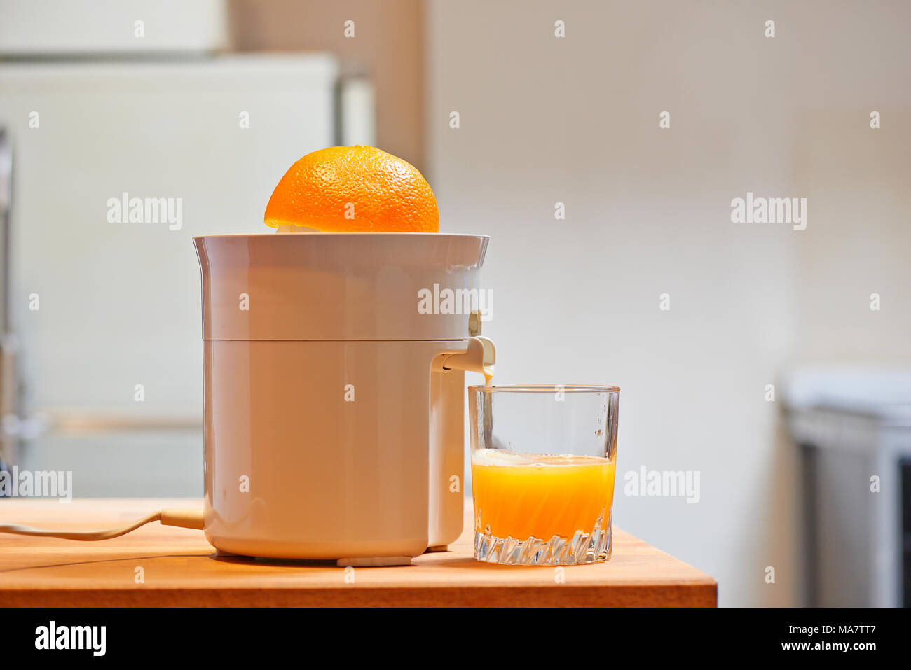 Spremiagrumi elettrico e succosa di vetro in una cucina moderna Foto Stock