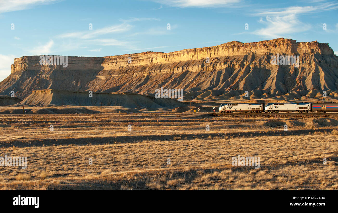 Un westbound Amtrack treno passa nella parte anteriore del portello Mesa vicino Floy, Utah al tramonto Foto Stock