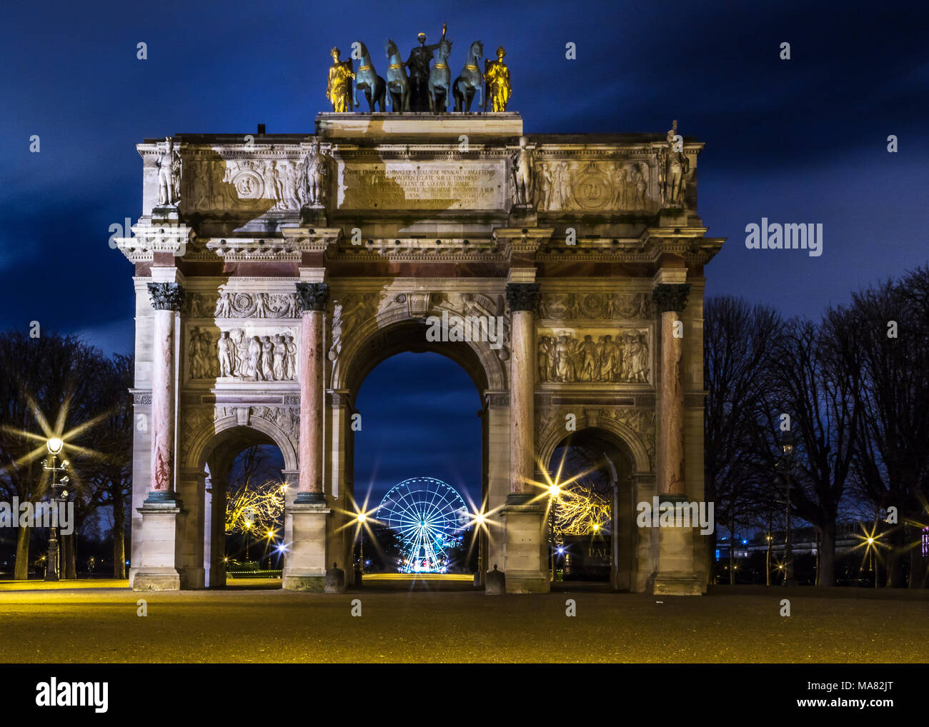 Arc de triomphe du giostra di notte il framing il Roue de Paris ruota attraverso l'arco centrale, affiancata da sagome ad albero e scintillanti luci di strada Foto Stock